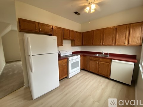 A kitchen with a white fridge and wooden cabinets.