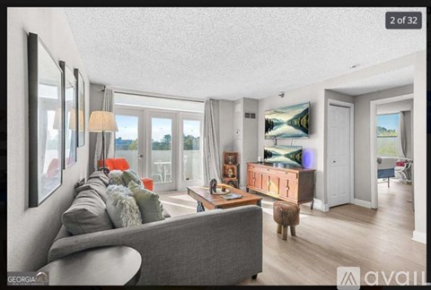 A living room with a grey couch and a painting on the wall.
