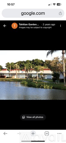 A serene view of a garden with a pond and a house in the background.