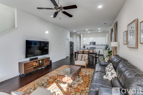 A living room with a black leather couch and a television on a wooden stand.