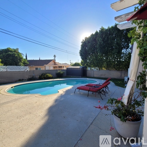 A pool with a red chair and a house in the background.