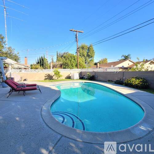 A pool with a red chair and a white fence in the background.