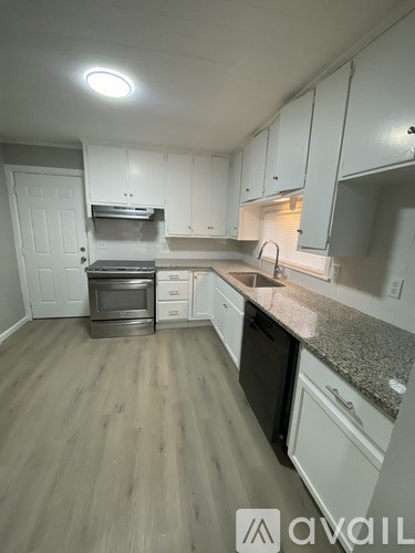 A kitchen with white cabinets and a granite countertop.