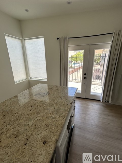 A kitchen with granite countertops and a sliding glass door leading to a balcony.