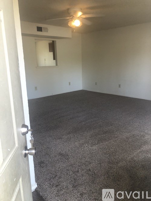A room with a carpeted floor and a ceiling fan.