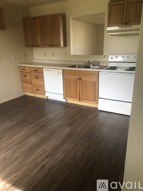 A kitchen with white appliances and wooden cabinets.