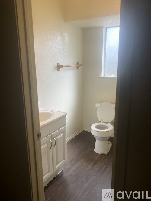 A white toilet in a small bathroom with a white sink and cabinet.