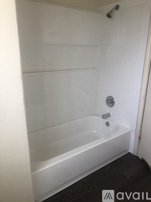 A white bathtub with a shower head and faucet.