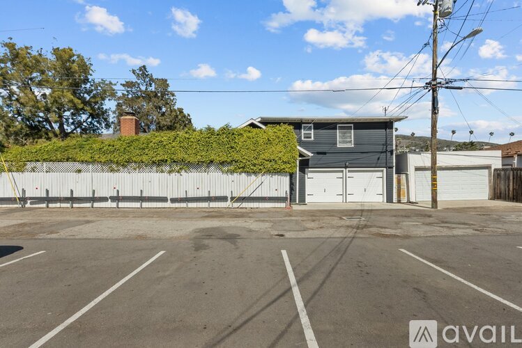 A parking lot with a building and a fence in the background.