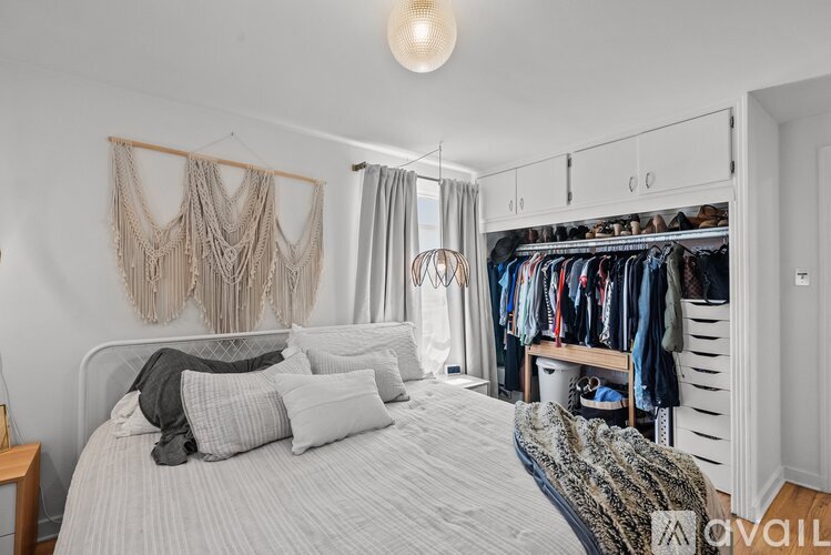 A bedroom with a large bed and a closet with clothes hanging.