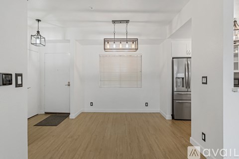 A kitchen with a refrigerator, oven, and a dining table with chairs.