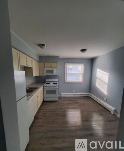A kitchen with white appliances and wooden floors.