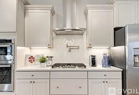 A kitchen with white cabinets and a stainless steel refrigerator.