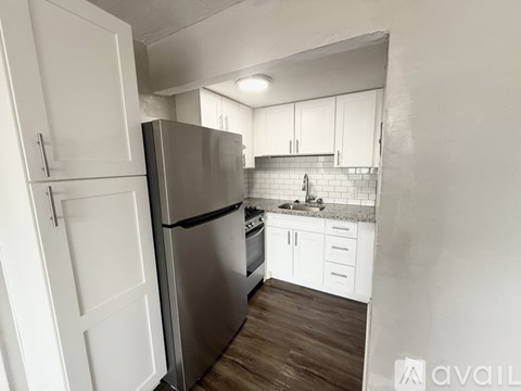 A kitchen with a refrigerator, sink, and cabinets.