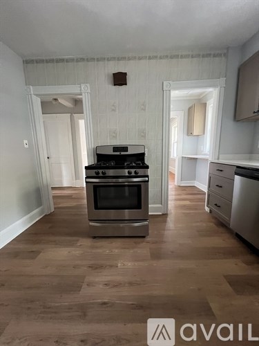 A kitchen with a stove and wooden floors.