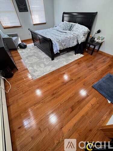 A bedroom with a black bed and wooden flooring.