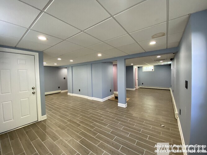 A spacious room with a white door and grey walls.