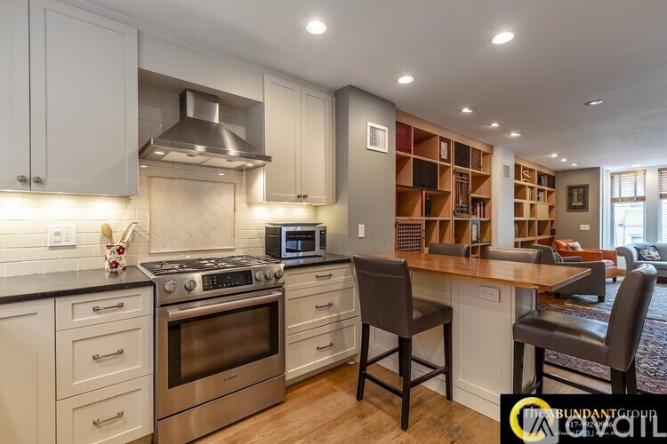 A kitchen with white cabinets and a black countertop.