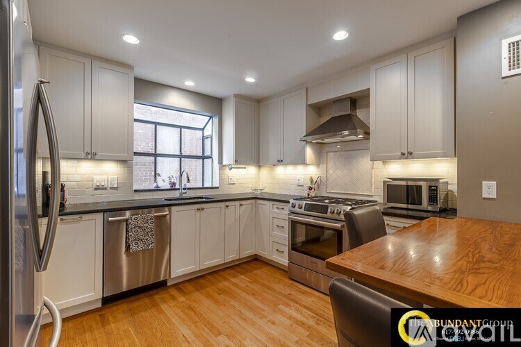 A kitchen with white cabinets and a wooden table.