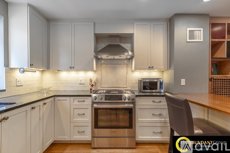 A kitchen with white cabinets and a black countertop.