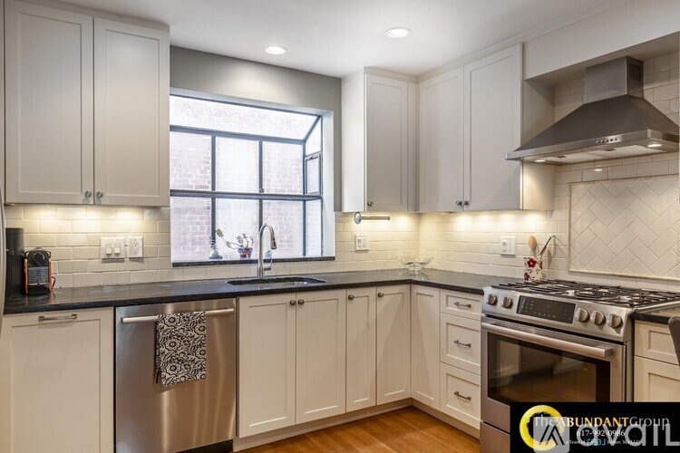 A kitchen with white cabinets and a black countertop.