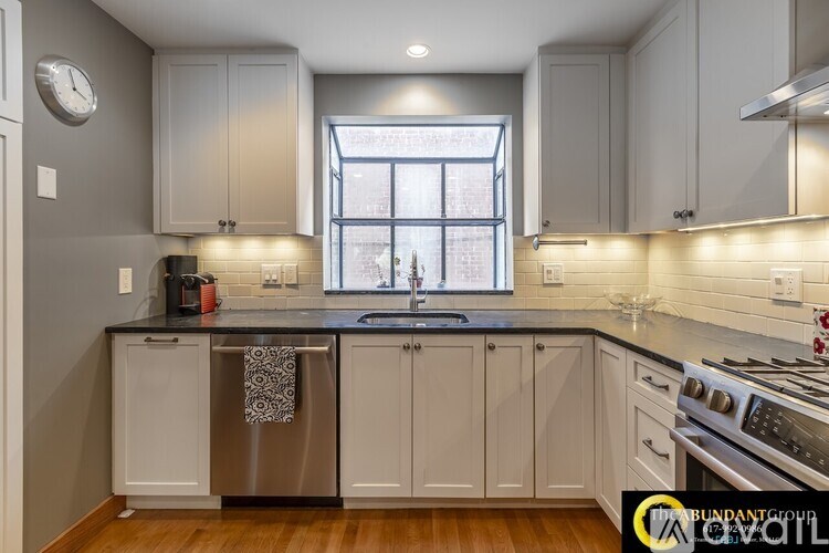 A kitchen with white cabinets and a black countertop.