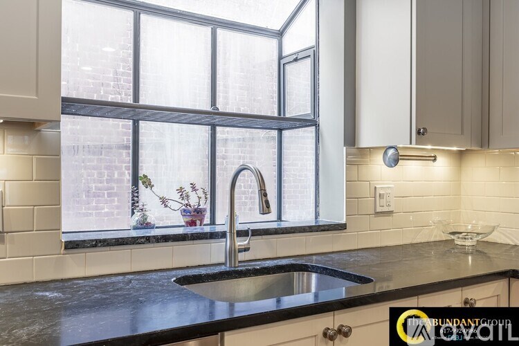 A kitchen with a black counter top and a window.