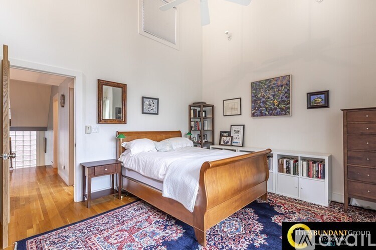 A bedroom with a large bed, a small table, and a rug on the floor.