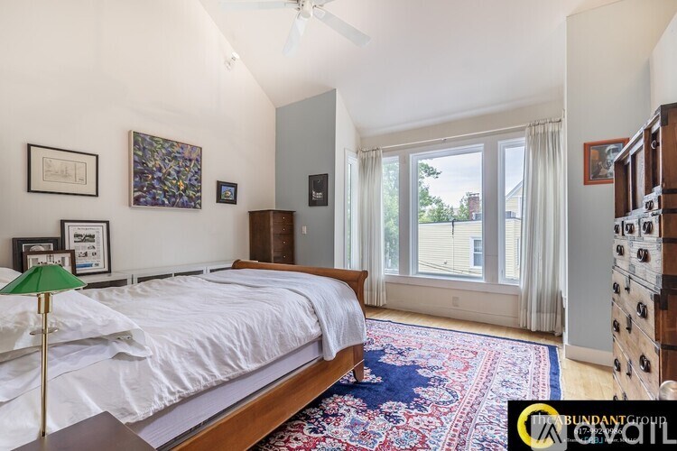 A bedroom with a bed, a rug, and pictures on the wall.