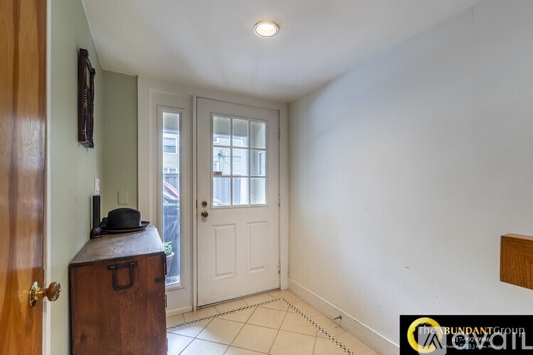 A room with a white door and a brown suitcase with a hat on it.