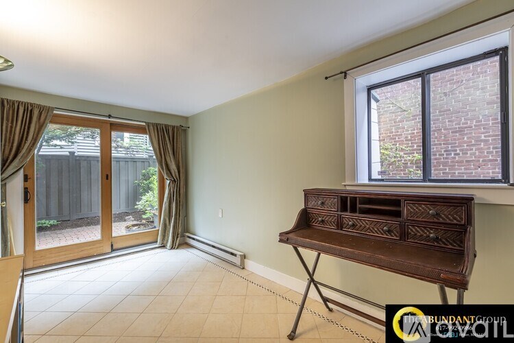 A room with a brown bench and a window with a view of a fence and trees.