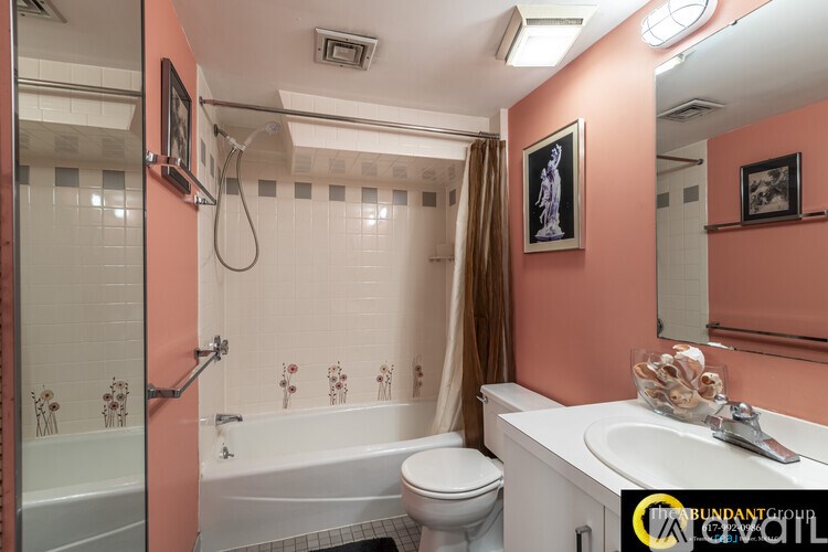 A bathroom with a pink wall and a white tub.
