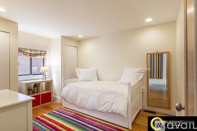 A bedroom with a white bed and a colorful rug.