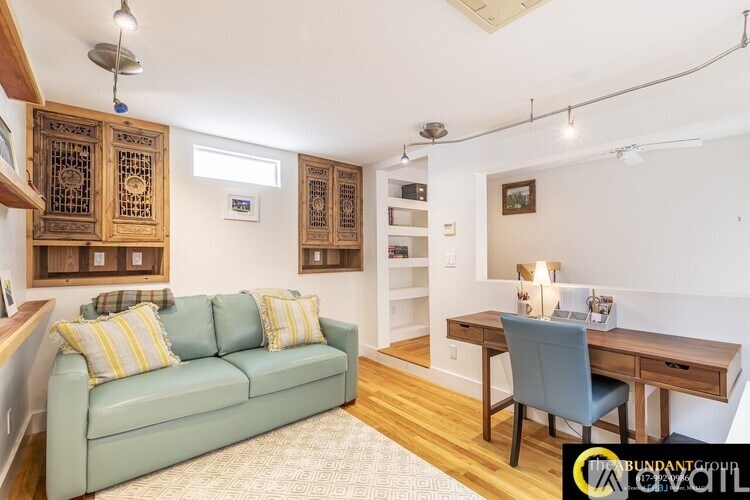 A living room with a green couch and a wooden desk.