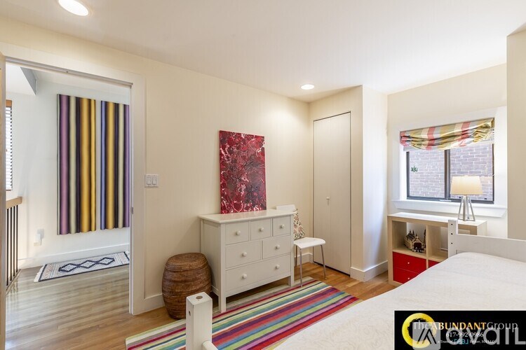 A bedroom with a white bed, a white dresser, and a white chair.