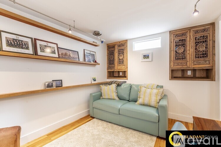 A living room with a green couch and wooden cabinets.
