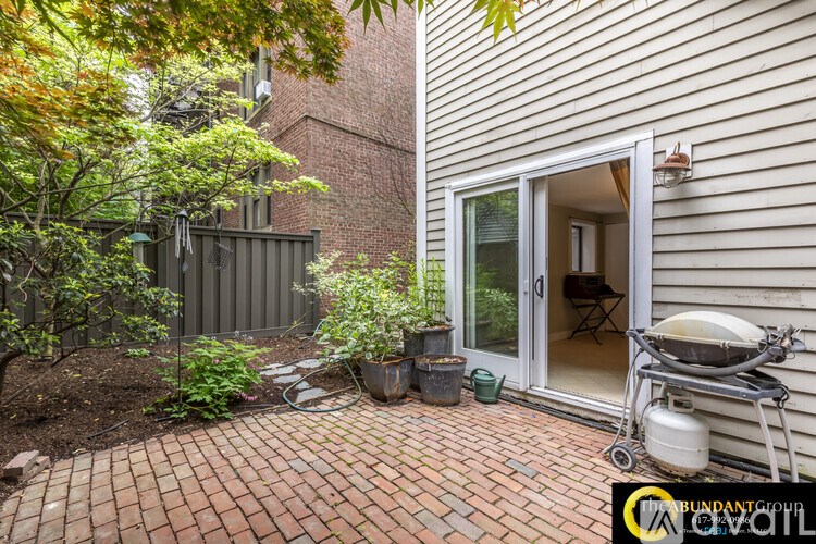 A patio area with a brick floor and a grill.
