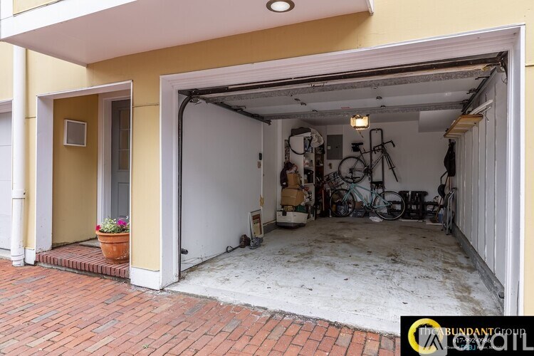 A garage with a brick floor and a bicycle hanging on the wall.