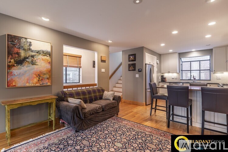 A living room with a couch, a chair, and a painting on the wall.