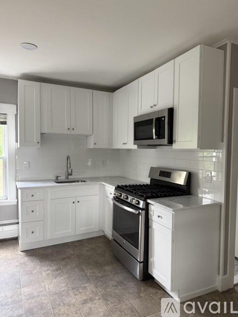 A kitchen with white cabinets and appliances.
