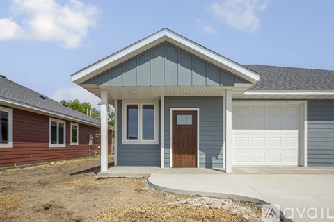 A blue house with a brown door stands in front of a red house.