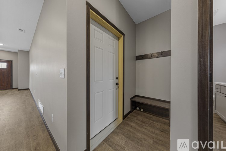 A hallway with a white door and a wooden floor.