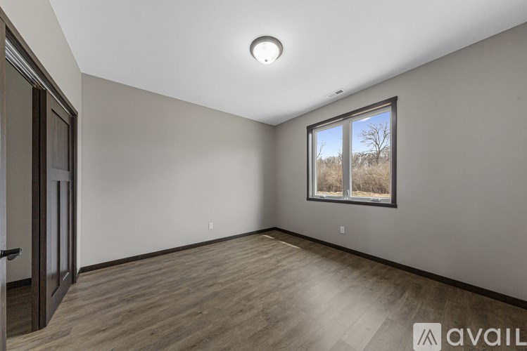 A room with wooden flooring and a window showing a field.