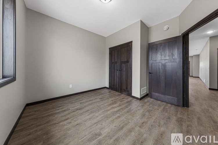 A spacious room with wooden flooring and a large door.