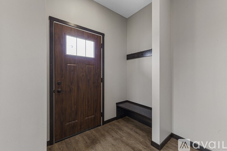 A wooden door with a window above it in a room with a bench.