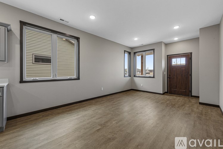 A spacious room with wooden flooring and a large window with blinds.