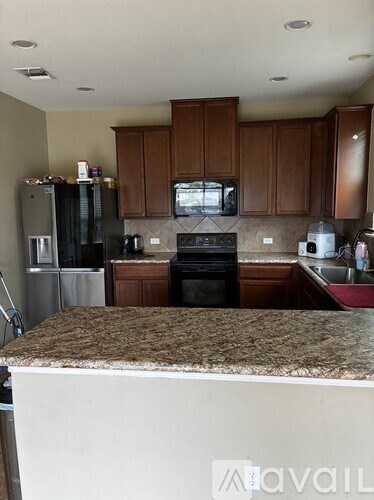 A kitchen with brown cabinets and a granite counter.