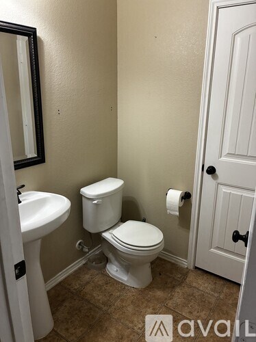 A bathroom with a toilet, sink, and a door.
