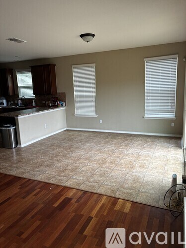 A kitchen with a brown floor and white walls.