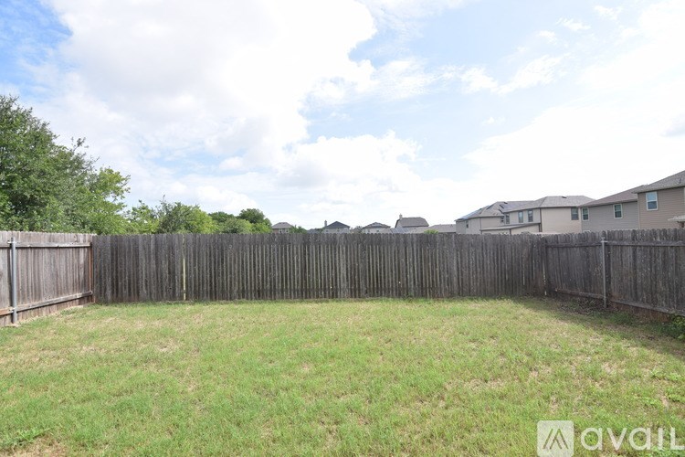 A backyard with a wooden fence and a grassy area.